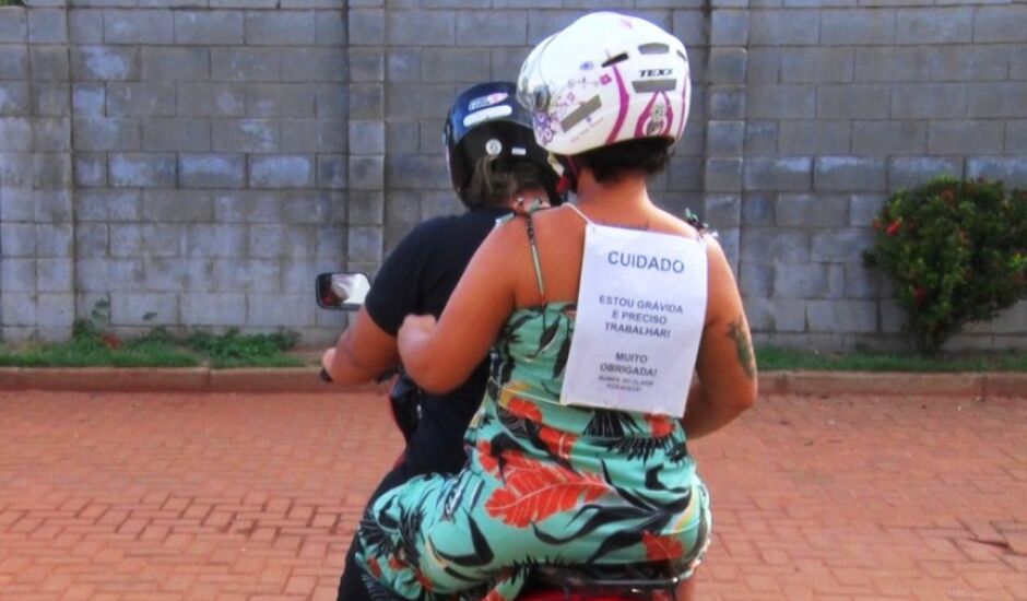 Em moto, grávida recorre à cartaz para garantir mais segurança à família.