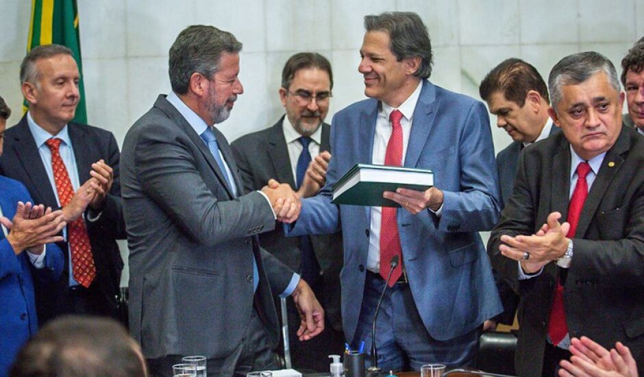 O presidente da Câmara, Arthur Lira, recebendo o texto das mãos do ministro da Fazenda, Fernando Haddad