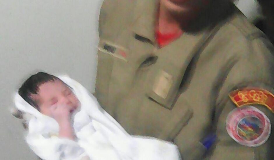 Soldado Wolney Santos segura a criança, após o parto em casa