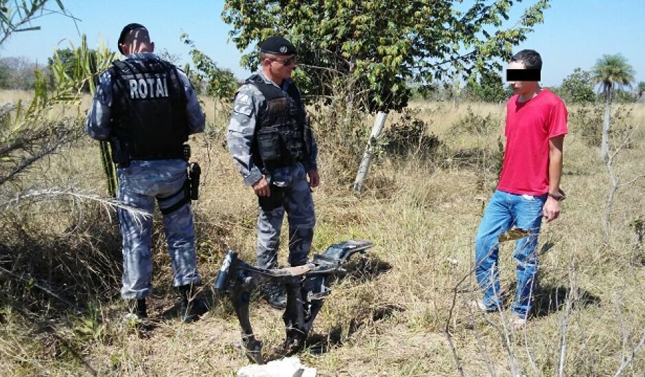 Policiais e um dos presos observam peças de motos escondidas em matagal