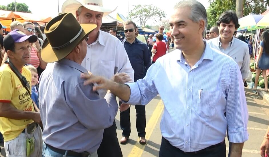 Governador cumprimenta moradores, ao lado de políticos de seu partido, em feira livre
