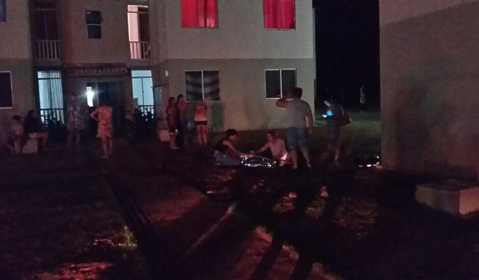 Pessoas observam corpo da vítima perto da casa