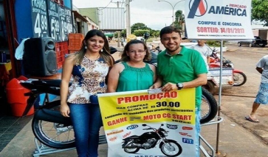 Mariana e Gilsimar, diretores do mercado, entregam moto à ganhadora da promoção