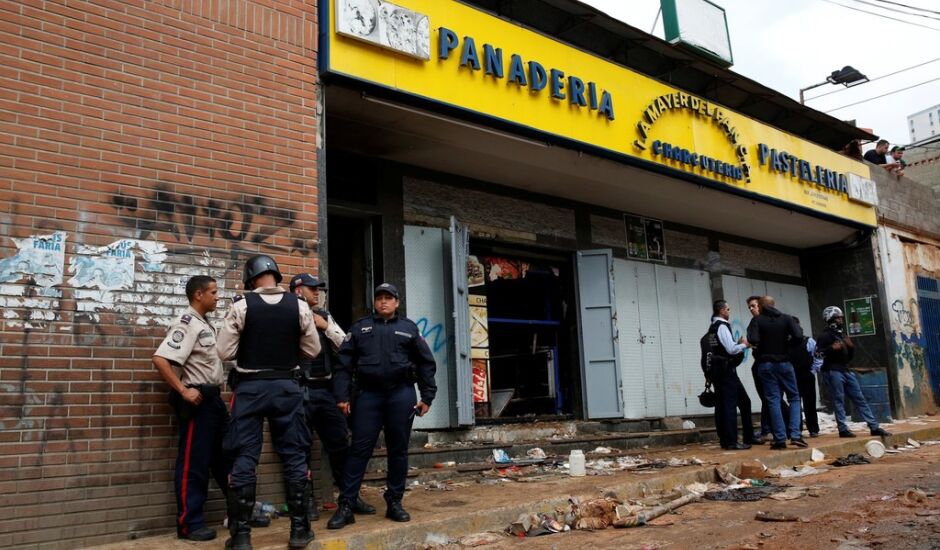Policiais e investigadores em frente à padaria saqueada em Caracas