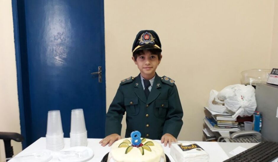 A criança vestiu a farda mirim a pedido de seus pais e sob o pretexto de visitarem seu padrinho, que é capitão da Polícia Militar
