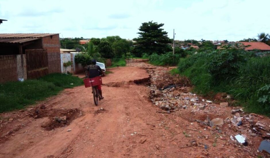 Ciclista tem dificuldade para passar por rua esburacada no bairro Daniel 5, em Paranaíba