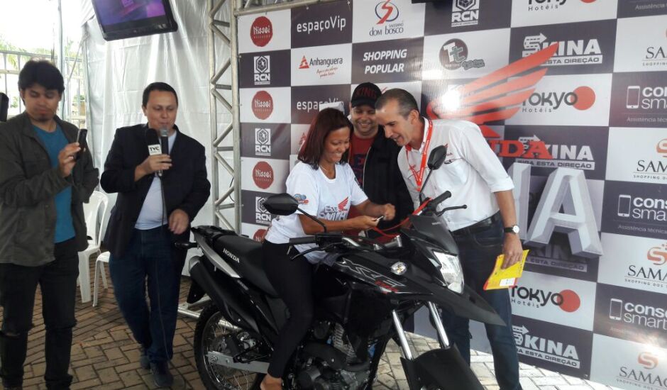 Clodoaldo Araújo, da Honda Mototrês, entrega moto à ganhadora Michele