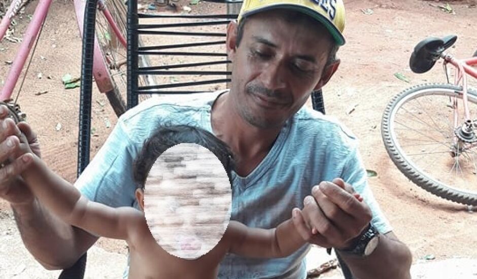 Gilberto, morto aos 41 anos, segura uma criança numa varanda