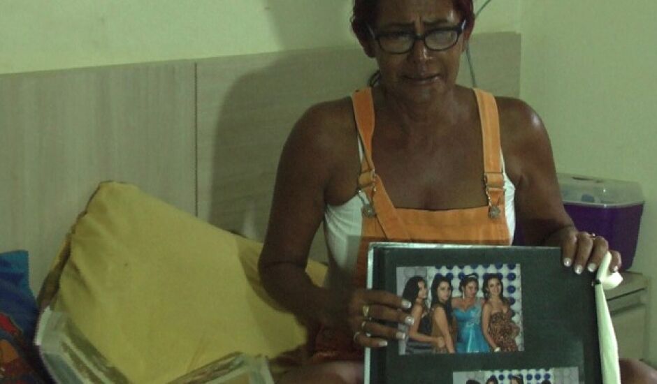 Maria Aparecida, mãe de Criskeila, segura álbum de fotos da festa de 15 anos da fillha, comemorado na Austrália